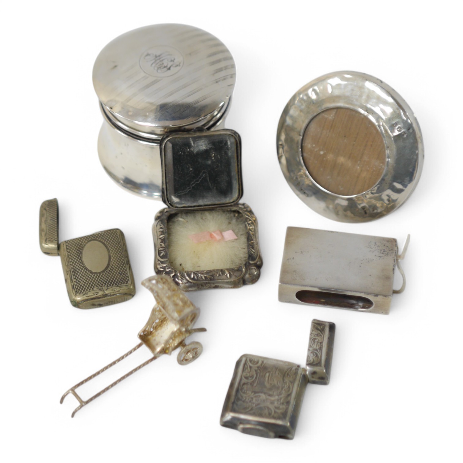 Assorted small collectables including a late Victorian silver vesta case, Birmingham, 1898, a small silver mounted circular photograph frame, a silver mounted glass pot and cover, a silver matchbox sleeve and three other